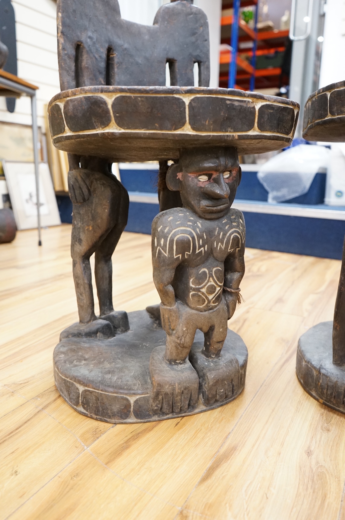 Papua New Guinea Sepik River, a near pair of ‘ceremonial’ figural chairs, each carved from a single section of a tree trunk with integral male and female backs and an castor figure front support with cowrie shell eyes. H